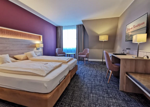 Blick in ein Doppelzimmer mit Doppelbett, Schreibtisch und Fernseher im Hotel Duhner Landhaus in Duhnen bei Cuxhaven